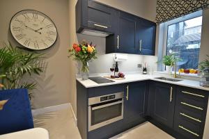 RawtenstallMoat House的厨房配有蓝色橱柜和墙上的时钟