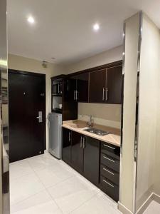 阿哈达Al Muhaidb Al Taif Hotel的厨房配有黑色橱柜和不锈钢冰箱