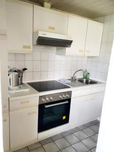 WangelsFerienwohnung Daliah的厨房配有白色橱柜、炉灶和水槽。