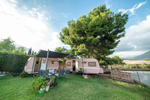 拉努西亚Caravana- Glamping Casa tortuga的粉红色的大篷车,有帐篷和一棵树