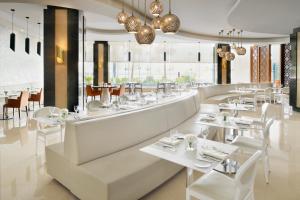 利雅德利雅得民哈尔皇冠假日酒店的餐厅设有白色的桌椅和窗户。