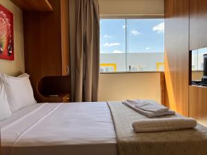 巴西利亚Multiparque Hplus Long Stay的一间卧室设有一张大床和大窗户