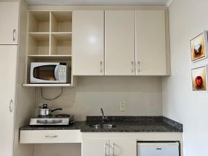 巴西利亚Multiparque Hplus Long Stay的厨房配有白色橱柜和微波炉