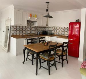 维尔纽斯Shabby Chic - apartment in the Heart of Vilnius Old Town的厨房配有木桌、椅子和红色冰箱。