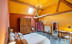 FernelmontGîte de la Ferme de Seron - gîte de charme avec bain nordique的卧室配有一张大床,位于拥有黄色墙壁的房间