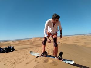 梅尔祖卡Nomad Bivouac的站在沙漠滑板上的人