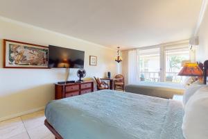 卡帕阿Islander on the Beach 211的一间卧室配有一张床、一张书桌和一个窗户。