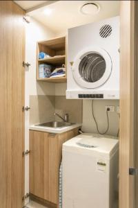 悉尼Lovely One Bedroom + Study with Infinity Pool的小厨房配有洗衣机和水槽