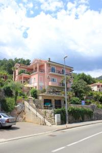 洛夫兰Apartments and rooms by the sea Medveja, Opatija - 2305的道路一侧的粉红色建筑