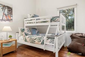 卡尔斯Rural 5 Star Villa's with Resort Amenities的一张白色双层床,位于一个配有沙发的房间