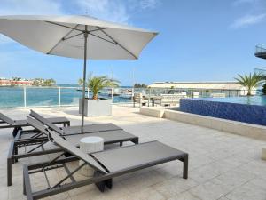 奥拉涅斯塔德ARUBA DREAM GETAWAY 2BR/2BT OCEAN & POOL VIEW的一个带椅子和遮阳伞的庭院和一个游泳池