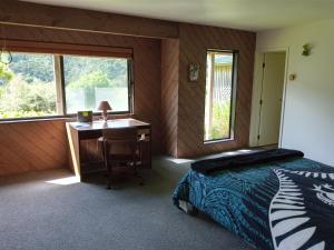 奥波诺尼Waiotemarama Falls Lodge的一间卧室配有书桌、一张床和一张书桌。