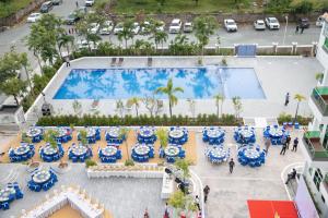 白马市Sangkahak Mith Hotel的享有带桌子和蓝白遮阳伞的游泳池的顶部景致