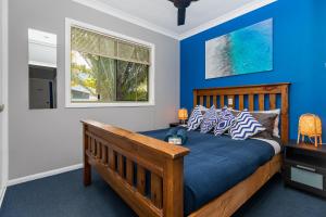 阿格奈什沃特KiteSurf 1770 Beach House的一间卧室配有一张蓝色墙壁的床和一扇窗户