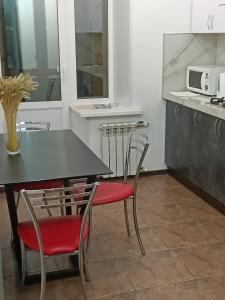彼得罗巴甫洛夫斯克Уютная и просторная квартира в 50 метрах от городского парка的厨房配有黑桌和红色椅子