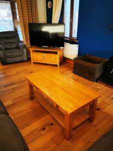 凯尔西温Picturesque Riverside Home的客厅配有木制咖啡桌和平面电视。