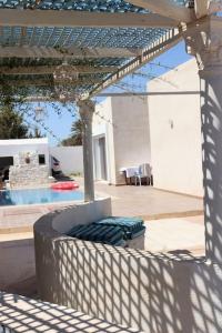 DjerbaMagnifique villa avec piscine的天井配有桌椅和吊灯。