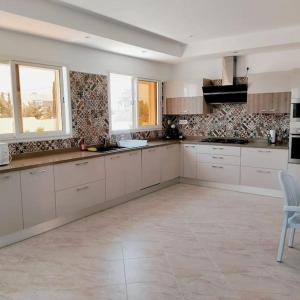 DjerbaMagnifique villa avec piscine的一间设有白色橱柜和窗户的大厨房