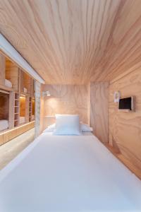 圣塞瓦斯蒂安Colo Colo Hostel - Single Private Beds的一张白色大床,位于带木墙的房间