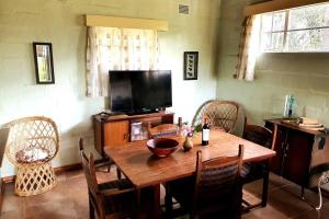 JuliasdaleRemarkable 3-Bed Cottage in Nyanga的一间带木桌和电视的用餐室