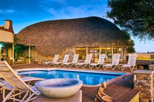 塞斯瑞姆We Kebi Safari Lodge的一座带椅子和游泳池的圆形建筑