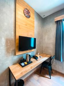 马贾伦卡Hotel Summerville的一间设有木桌的客房,墙上配有电视