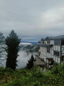 西姆拉Sugar Cube Retreat的山丘上享有云景的房子