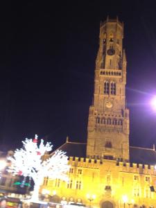 布鲁日Bruges Grande Place Guesthouse的一座高大的塔,晚上有钟