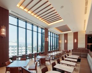 熊本Candeo Hotels Kumamoto Shinshigai的餐厅设有桌椅和大窗户。