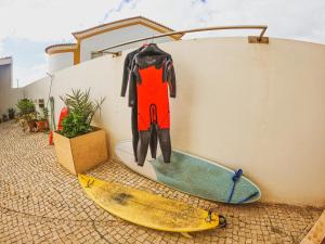 巴勒尔Cosmos Retreat Baleal的挂在两个冲浪板旁边的墙上的湿衣
