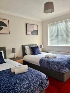 梅德斯通Delight Marvel- Beech Hurst-3 bedroom house的一间卧室配有两张带蓝白色床单的床