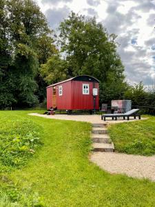 MountnugentSheelin Shepherds Hut 2 with Hot Tub的坐在公园里带长凳的红色棚子