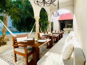 梅里达外交官精品酒店的餐厅拥有木桌和椅子,并种植了棕榈树。