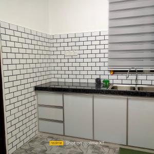 日得拉Homestay Tengku Maheran的厨房设有白色瓷砖墙壁和水槽