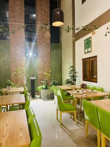 尼甘布J Leaf Hotel By Blue Bird的餐厅设有木桌和绿色椅子