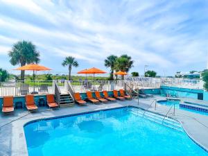 默特尔比奇Palette Resort Myrtle Beach by OYO的一个带橙色椅子和遮阳伞的游泳池