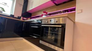 阿斯隆#3 TGHA Luxury One Bedroom Apartment in Athlone的厨房里设有黑色烤箱,配有紫色照明