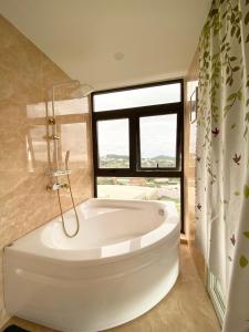 大叻Bảo Châu Villa & Coffee Đà Lạt的带窗户的浴室内的白色浴缸