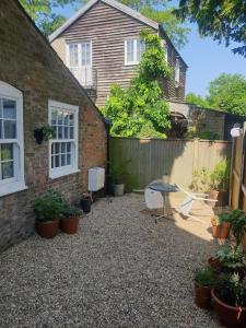 WalmerWalmer, Deal stunning coach house apartment的房屋前设有带桌椅的天井。