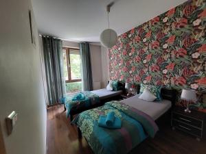 什切青SAS Apartamenty Baron的一间卧室设有两张床和一张带花卉壁纸的墙壁