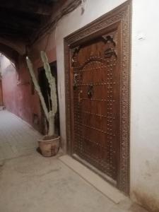 马拉喀什Hostel Laksour的木门,在有盆栽的房间里