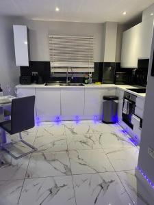 埃奇韦尔2 Double Bedroom Apartment in Edgware, London的厨房配有白色柜台和带紫色灯的电器