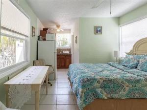 萨拉索塔Charming Studio Unit Across from Lido Key Beach的一间卧室配有一张床铺、一张桌子和一台冰箱