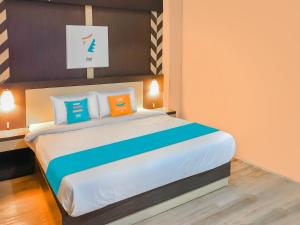帕朗卡拉亚Sans Hotel City Inn Palangkaraya的一间卧室配有一张带橙色和蓝色枕头的大床