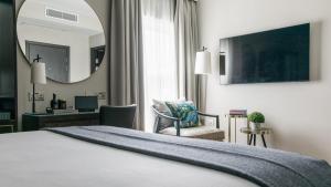 泰晤士河畔里士满The Selwyn, Richmond的酒店客房带一张床、一张书桌和一面镜子