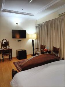 多哈艾卡瑞斯酒店的一间卧室配有一张床、一张书桌和一台电视