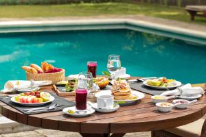 康提The Lavender House by Reveal的一张桌子,旁边是游泳池,摆放着食物和饮料