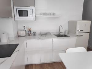 卢戈Apartamentos CANDEA的白色的厨房配有水槽和微波炉