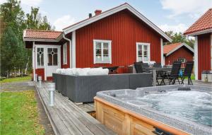 卡尔斯塔德Gorgeous Home In Karlstad With Sauna的红房子旁边的甲板上的热水浴缸