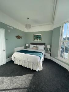 滕比Ivy Bank Guest House, Tenby的一间卧室设有一张大床和两个窗户。